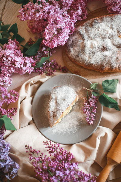 Homemade Apple pie on a wooden table next to a bowl of lilacs. Gentle toning. Selective focus. - Foto, Bild