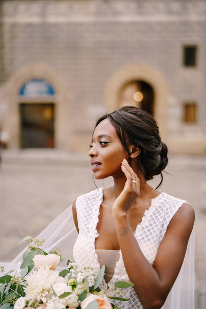 Boda en Florencia, Italia. Novia afroamericana con un vestido blanco y un largo velo. Con un magnífico ramo de la novia en sus brazos
. - Foto, Imagen