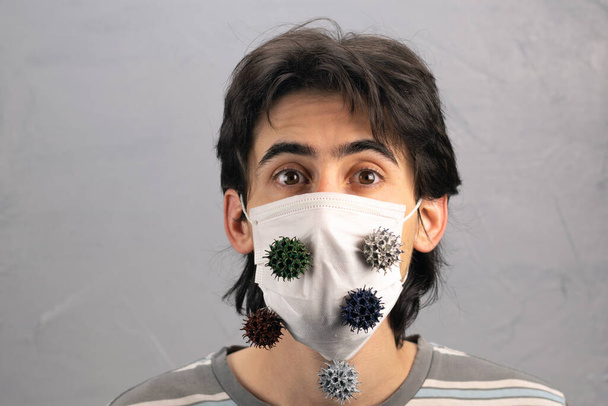 Junger Mann mit einem Kinnriemen mit dem Covid-19-Virus am Kinnriemen - Foto, Bild