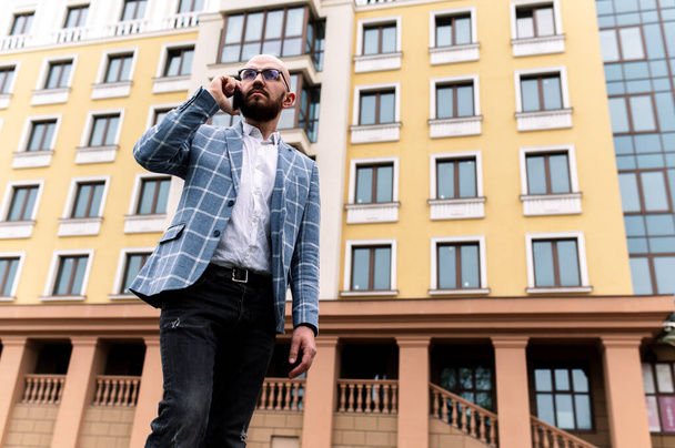 Egy öltönyös üzletember egy gyönyörű épület hátterében, aki telefonon beszél. szabadtéri - Fotó, kép
