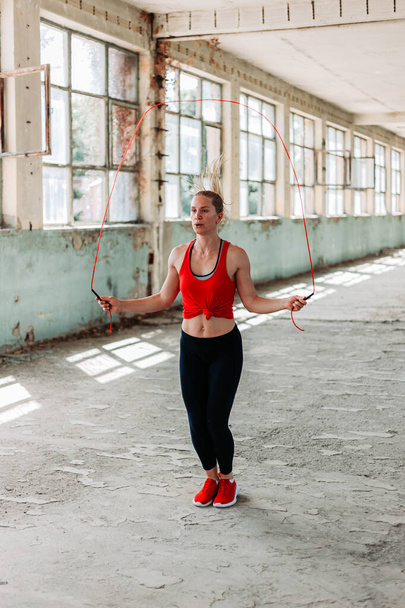 Athletic fit girl rope jumping. Fitness training, healthy lifestyle. Indoors shot in an old building - Foto, Imagem