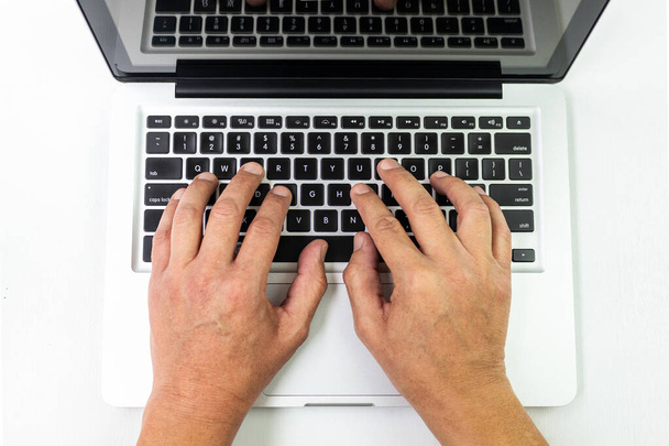 Tiro de cima de mãos que trabalham em um computador de cor clara em um fundo branco
 - Foto, Imagem