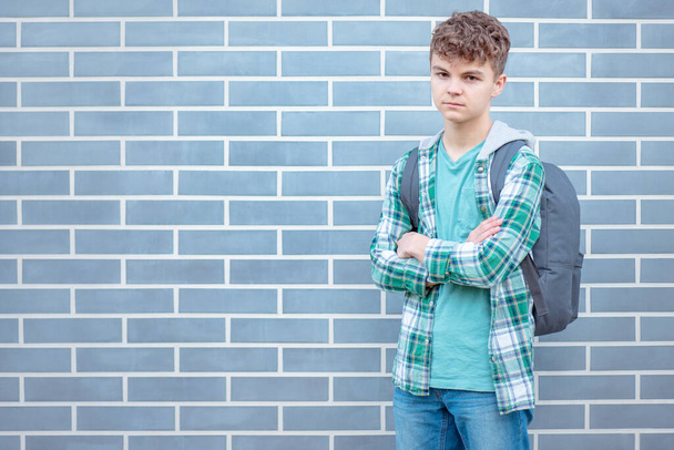 Schoolchild go to school with backpack. Serious cute child - teen boy with bag against a brick wall outdoors. Childhood and Back to school concept. - Foto, afbeelding