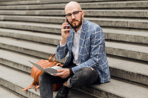  επιχειρηματίας κάθεται στο χάλια και μιλάει σε ένα κινητό τηλέφωνο - Φωτογραφία, εικόνα
