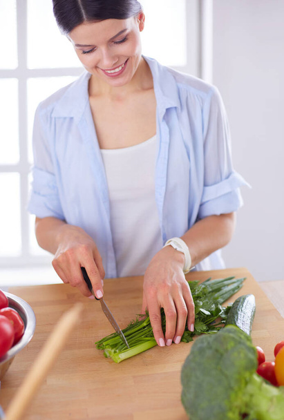 Young woman cutting vegetables in kitchen at home. - Photo, image