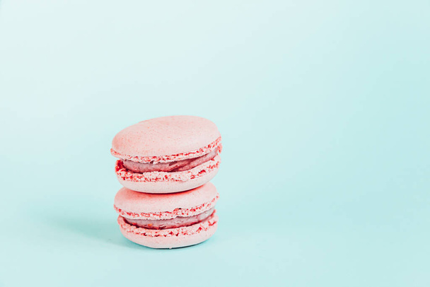 Sweet almond colorful unicorn pink macaron or macaroon dessert cake isolated on trendy blue pastel background. French sweet cookie. Minimal food bakery concept. Copy space - Photo, Image