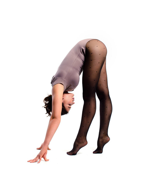 Stretching exercises. A gymnast in a bodysuit performs a head-down stand. Training elements of acrobatics on a white background - Photo, image