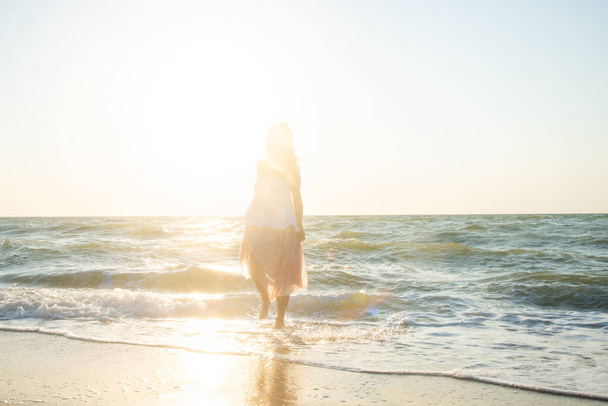 young beautiful woman enjoying the beach on a sunny summer day at sunset.  - 写真・画像