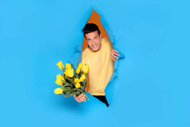 Smiling teenage boy with bouquet of yellow tulip flowers. Mother's Day Greeting Card. Happy mothers day.Women's Day. Copy space. - Photo, Image