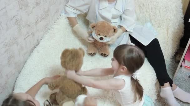 healthy children plays in hospital. children girls play with toy bears in medical protective masks. game pretends to be doctor, nurse, veterinarian - Footage, Video