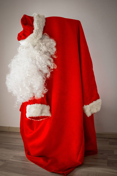 Czerwony strój Świętego Mikołaja wisi na krześle. Wkrótce wakacje są w przygotowaniu, poszukiwanie prezentów. Cieszę się, że twoi bliscy, realizują swoje marzenia! Lekkie tło, winietowanie. - Zdjęcie, obraz