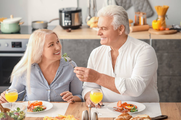 Feliz pareja de ancianos desayunando en casa
 - Foto, Imagen