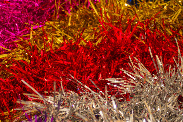Bright stripes of shiny tinsel. New Year's, festive background. Macro photography, artificial lighting. - Photo, Image