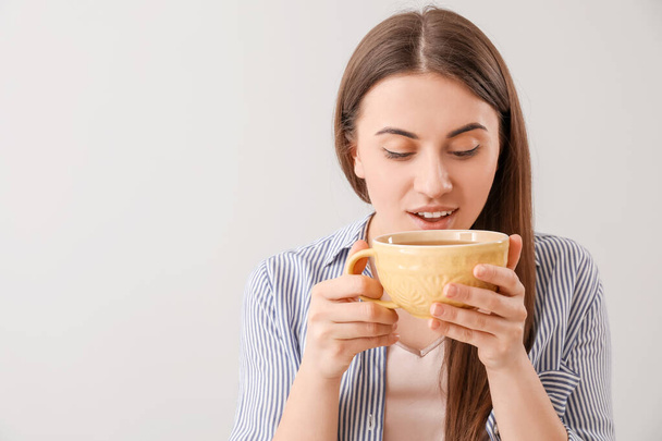 Mujer joven en taza de té sobre fondo gris
 - Foto, imagen