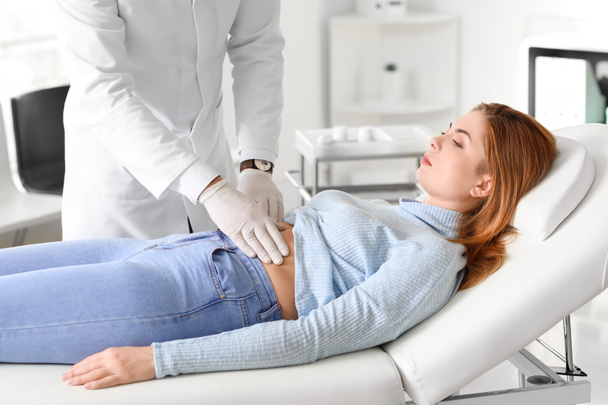 Gastroenterologist examining woman in clinic - Fotoğraf, Görsel
