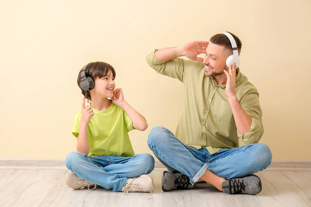 Padre e hijo pequeño escuchando música cerca de la pared de color
 - Foto, imagen