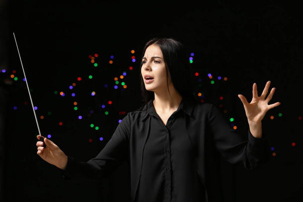 Young female conductor on dark background - Photo, Image