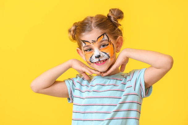 Funny little girl with face painting on color background - Photo, Image