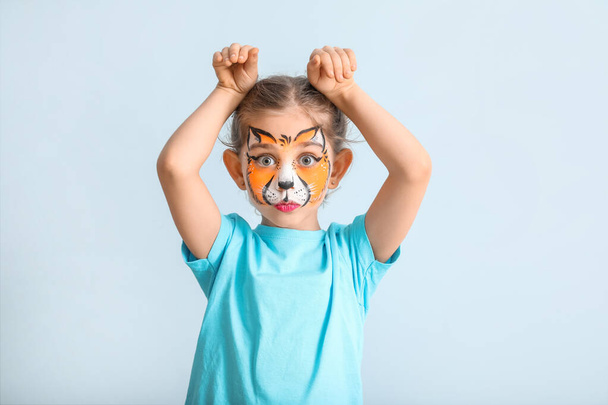 Funny little girl with face painting on color background - Photo, Image