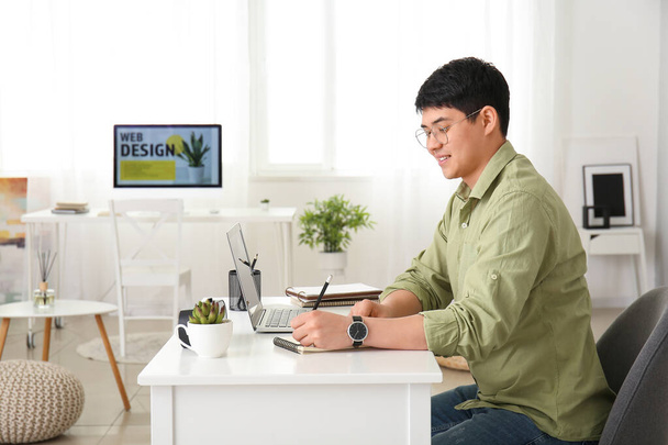 Молодой азиат работает дома на ноутбуке
 - Фото, изображение