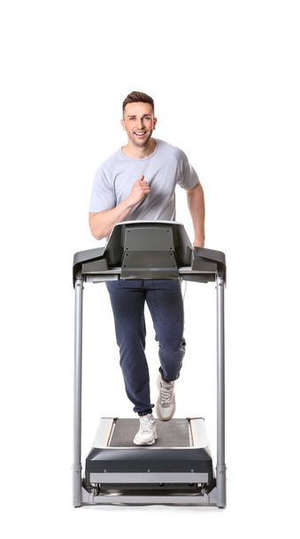 Sporty young man training on treadmill against white background - Valokuva, kuva
