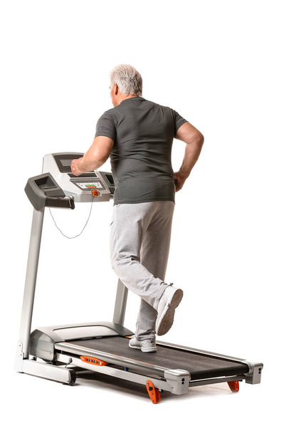 Senior man training on treadmill against white background - Photo, Image