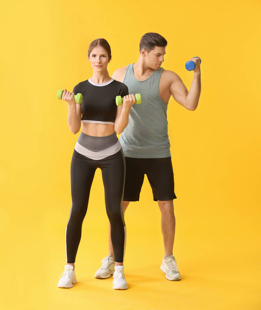 Sporty young couple with dumbbells on color background - Foto, Imagem