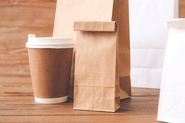 Paper bags and cup of coffee on wooden background - Foto, imagen