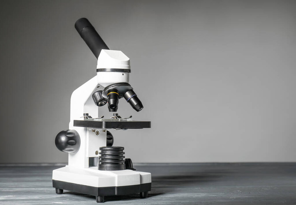 Modern mikroszkóp az asztalon szürke háttérrel - Fotó, kép