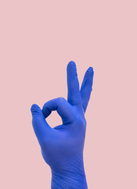 kéz orvosi kesztyű csinál az OK gesztus, szimbolizálja a győzelem koronavírus COVID-19. - Fotó, kép