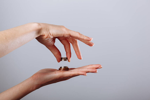 Frauenhand, die Goldmünze in eine andere Hand gibt oder nimmt, auf isoliertem weißem Hintergrund, Krisenkonzept. - Foto, Bild
