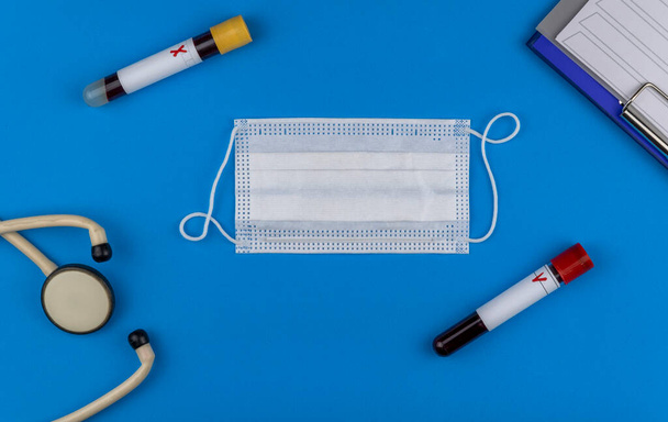 Flat lay composition with blood test tube on blue background. antiviral medical mask for protection against coronavirus COVID-19. concept of diagnosis of virus. copy space - Foto, Imagen