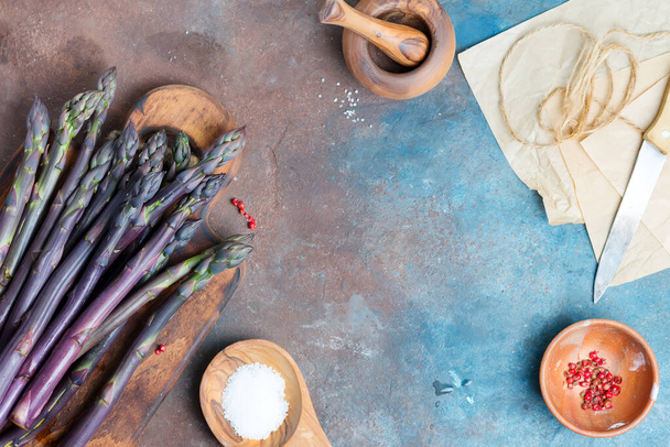 Сирий органічний фіолетовий спаржа списи на дерев'яній дошці як здорове дієтичне харчування на фоні темного каменю
. - Фото, зображення