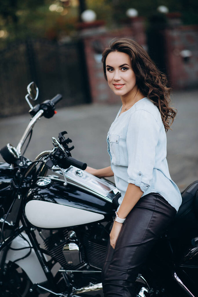 Young beautiful biker girl in a blue shirt on a motorcycle. The concept of speed and freedom. Soft selective focus. - Photo, Image