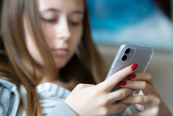 Entediada adolescente olhando para o celular. Foco seletivo
 - Foto, Imagem
