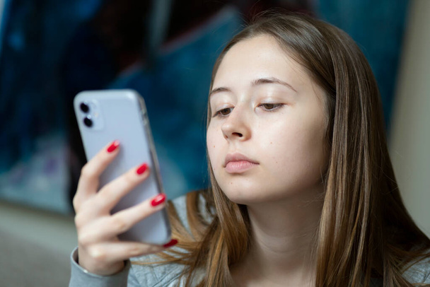 Una ragazzina annoiata che guarda il suo cellulare. Focus selettivo
 - Foto, immagini