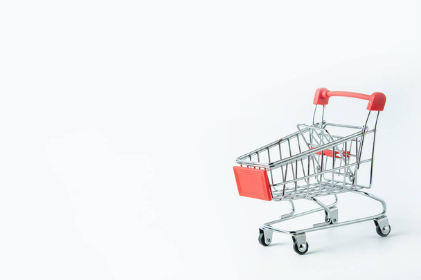 Concepto de compras: Carrito de compras rojo sobre fondo blanco con espacio de copia
 - Foto, imagen