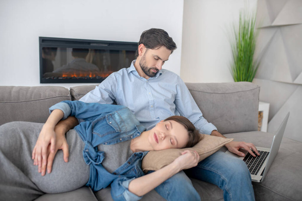 Jovem grávida em uma jaqueta jeans dormindo em seus maridos voltas
 - Foto, Imagem