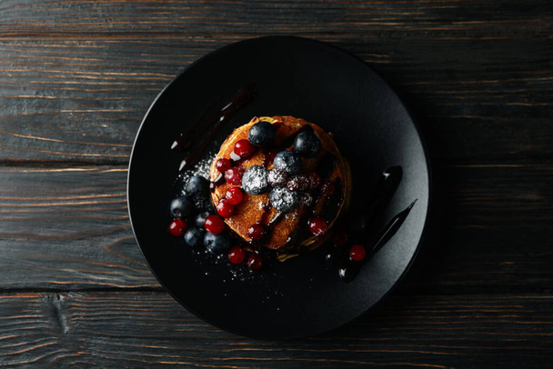 Plate with pancakes and berries on wooden background. Sweet breakfast - Photo, image