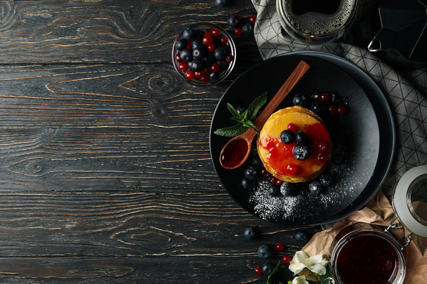 Plate of tasty pancakes with berry and powder on wooden table. Composition of sweet breakfast - Photo, Image