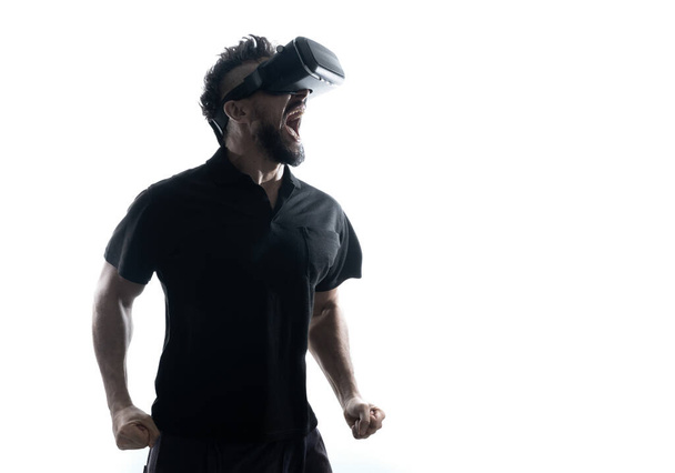 Man in dark T-shirt wearing virtual reality 3D headset glasses like a winner - Фото, зображення