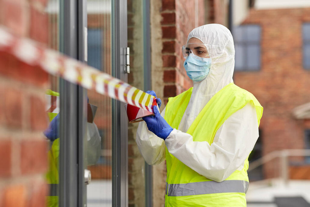 healthcare worker sealing door with caution tape - Φωτογραφία, εικόνα