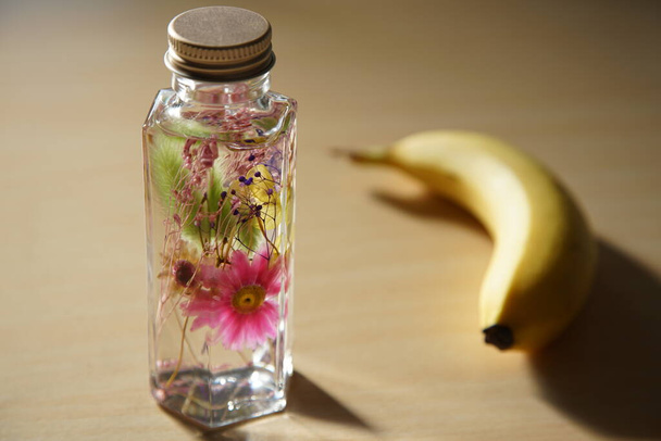 Decoración floral en botella de vidrio con plátanos sobre la mesa - Foto, Imagen