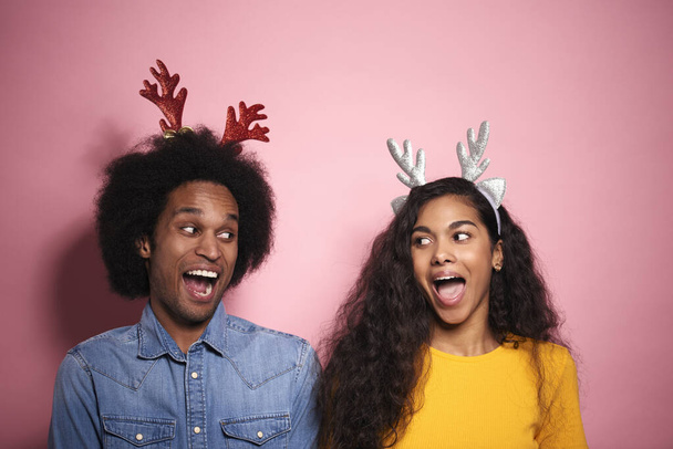 African couple screaming in reindeer headbands in studio shot. - 写真・画像