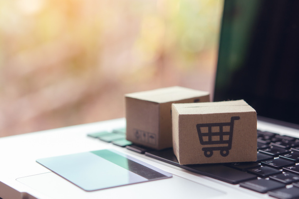 Online shopping - Paper cartons or parcel with a shopping cart logo and credit card on a laptop keyboard. Shopping service on The online web and offers home delivery. - Photo, Image