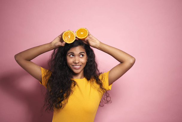 Young African woman having fun with oranges in studio shot - Photo, Image