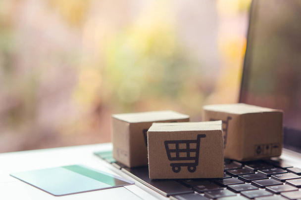 Online shopping - Paper cartons or parcel with a shopping cart logo and credit card on a laptop keyboard. Shopping service on The online web and offers home delivery. - Fotó, kép
