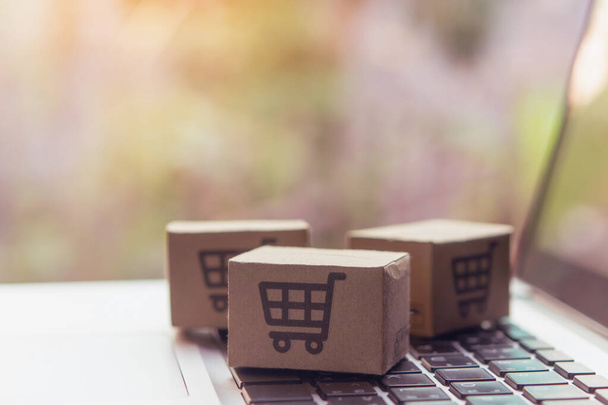 Online shopping - Paper cartons or parcel with a shopping cart logo on a laptop keyboard. Shopping service on The online web and offers home delivery. - Fotó, kép