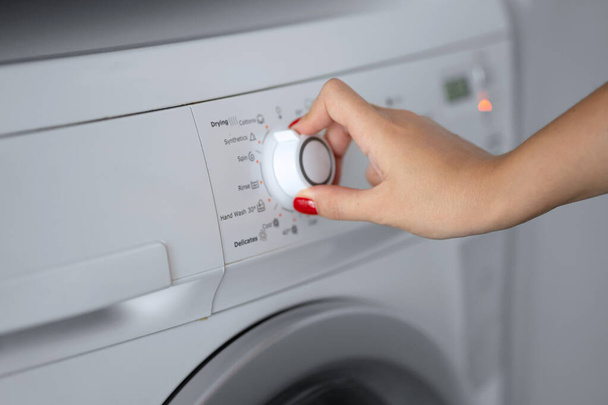 The girl sets the washing program for the washing machine - Φωτογραφία, εικόνα