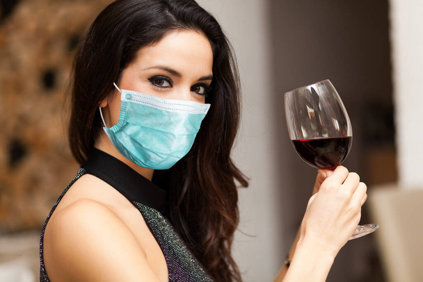 Belle femme tenant un verre de vin rouge portant un masque, concept de coronavirus
 - Photo, image
